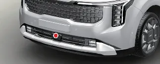 Location of the primary front radar sensor on the Kia Carnival front bumper